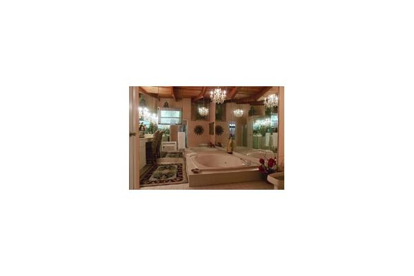 There is a fabulous mirrored bath, a separate shower and bidet. A chandelier hangs over a huge tub for two with Jacuzzi. 