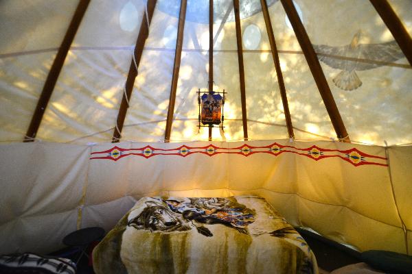 Tepee #1 inside looking double bed, bunk bed cots to left and right 